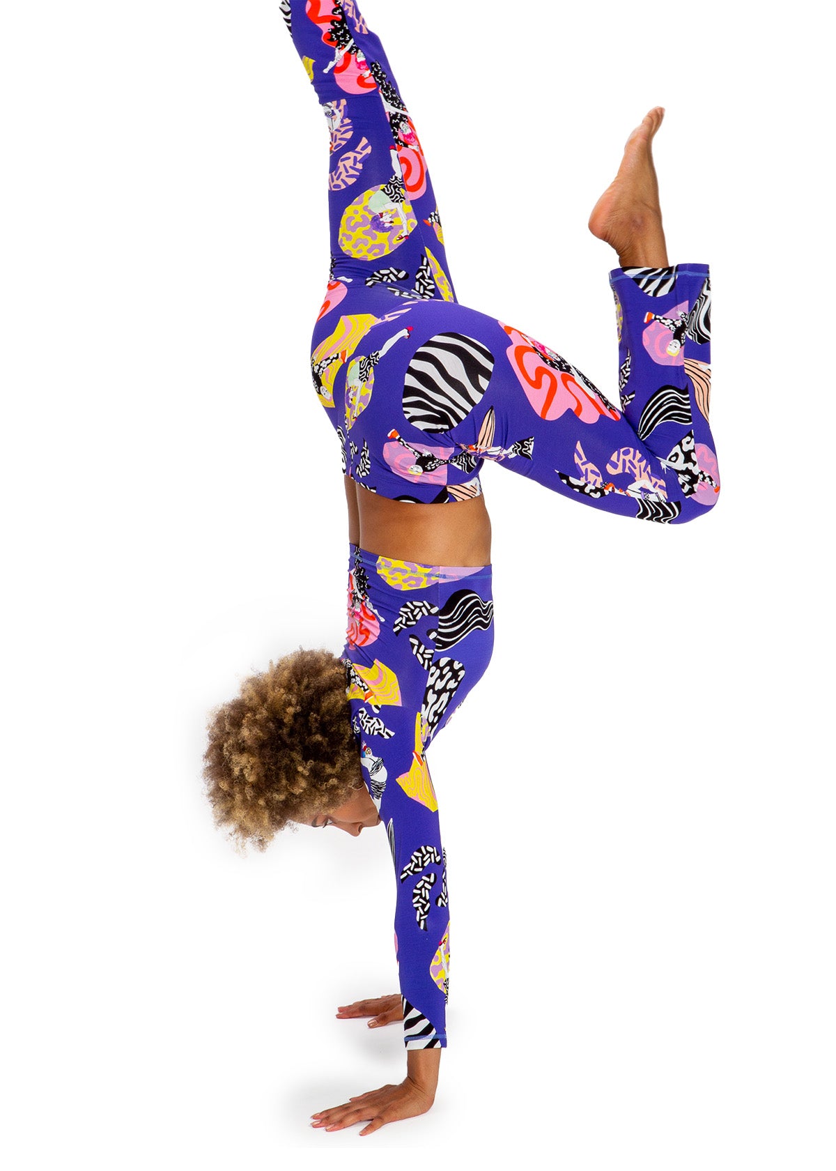 Person wearing colorful leggings with a zebra pattern, performing a handstand on a white background